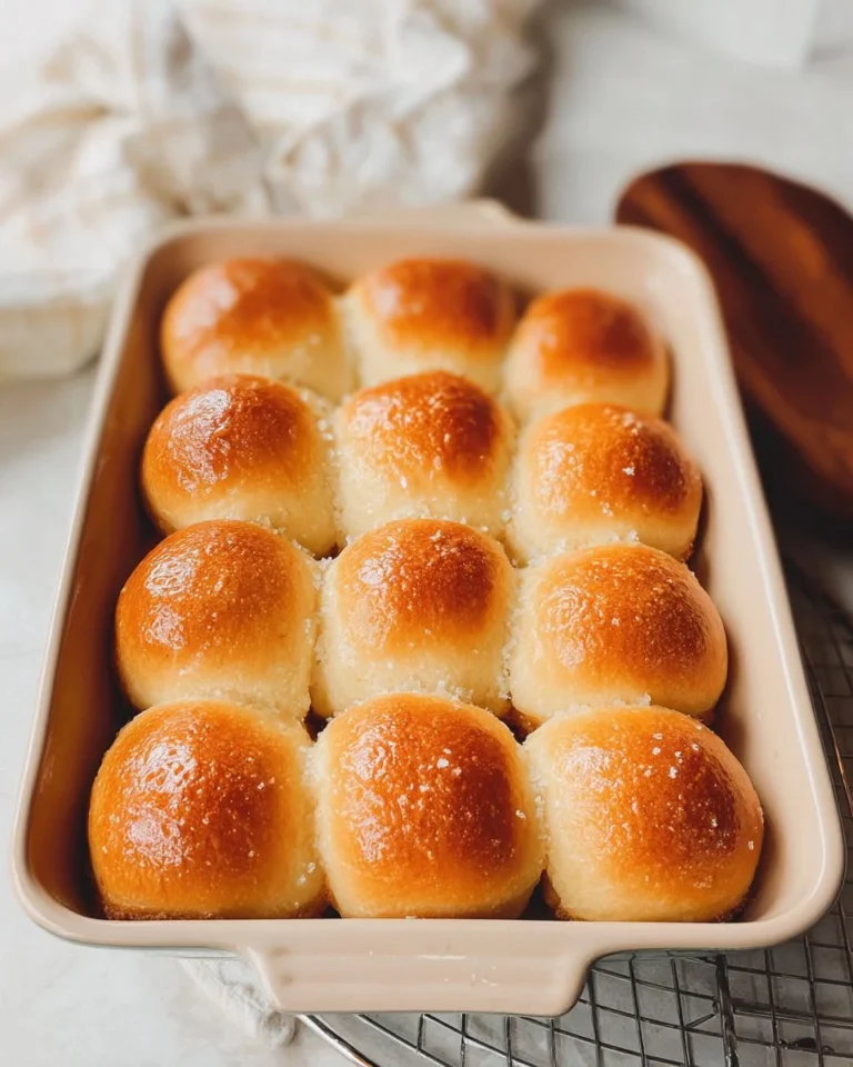 Freshly baked sourdough dinner rolls on a wooden table