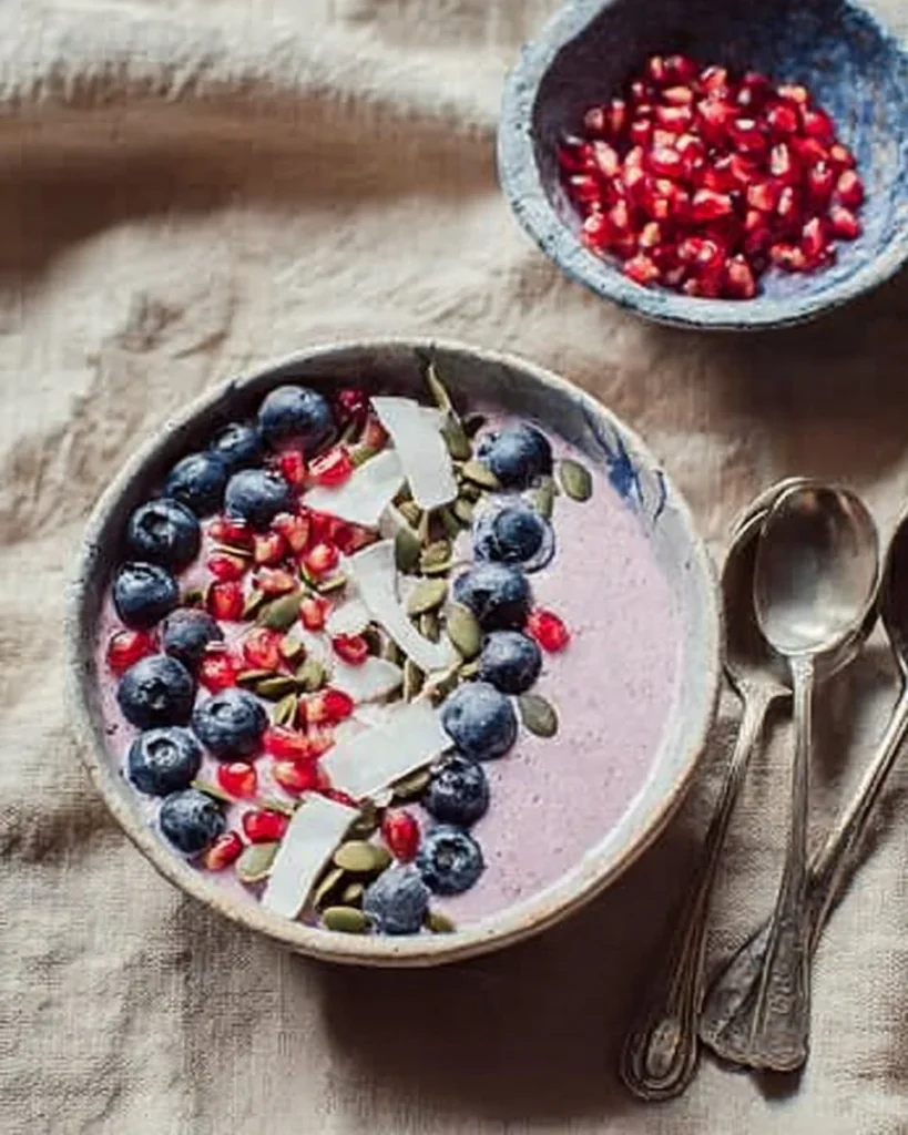 Delicious pomegranate smoothie bowl topped with fresh fruits and nuts