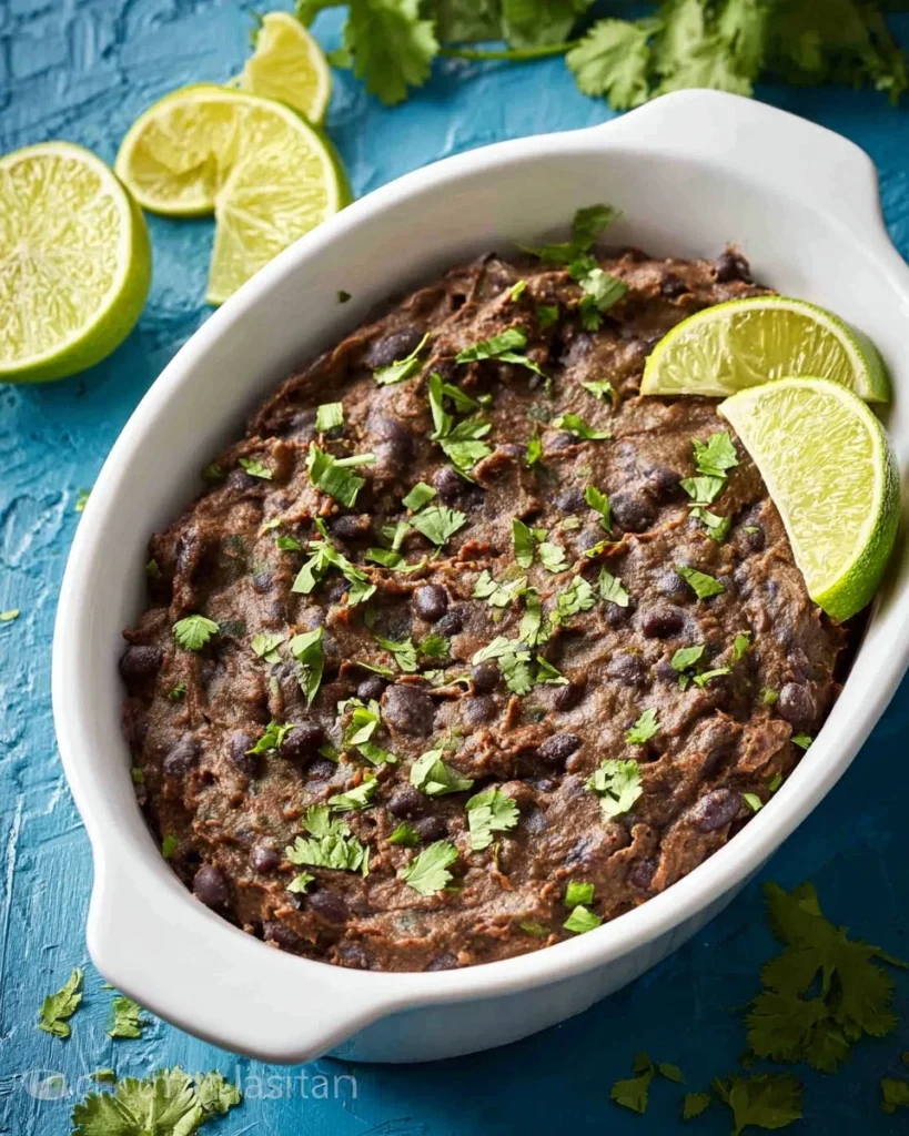 Bowl of easy refried black beans with spices and green onions